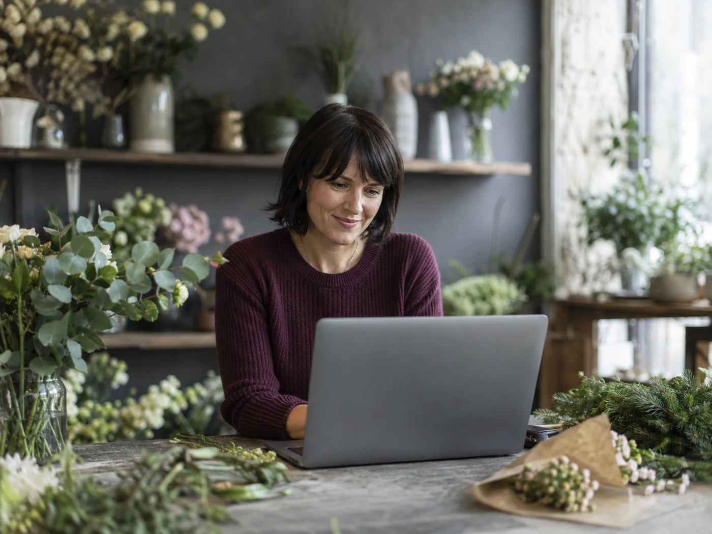 Floristin organisiert die Büroarbeit ihres Blumenladens am Laptop